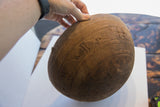 Hand-carved texture and incised patterns on an antique African wooden bowl, revealing a crack.