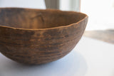Rich, dark brown wood texture on the antique African carved bowl's exterior with incised lines.
