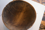 Antique wooden bowl interior with deep cracks and an old wire repair.