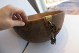 Textured dark wood of the antique hand carved bowl, showing incised pattern and metalwork repair.