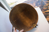 Interior of antique African carved bowl, featuring dark wood grain, visible cracks, and brass repair.
