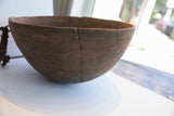 Deep vertical crack and incised patterns on the aged dark wood of an antique African bowl.