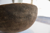 Antique African wooden bowl's rim, showing a significant crack and aged dark wood.