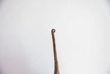 Close-up of the rusted, textured iron finial of the handmade African Yoruba bell.