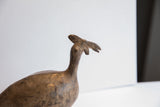 Stylized head and crest of a vintage African bird casting showing its aged, matte texture.