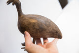 Hand holding the vintage African bird casting, showing its scale and aged texture.