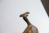 Upward view of the stylized head and crest on a vintage African bird casting.