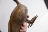 View of the aged, textured underside and cast feet of the African bird figure.