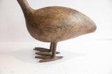 Low-angle view of the vintage African bird's weathered body, cast legs, and webbed feet.