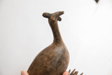 Low-angle view of the vintage African bird casting's stylized head and textured neck.