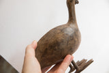 Vintage African bird casting held in hand to show its scale and tactile, aged surface.