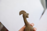 Handheld view of the vintage bird casting's head, showing the detailed comb and rustic patina.