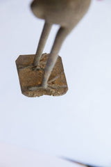 Close-up of the vintage bird casting's rustic metal feet and textured square base.