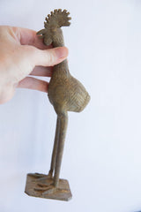 Side view of a collectible African bird casting held in hand to show its scale.