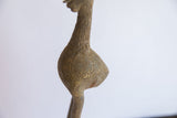Etched feather-like patterns on the aged bronze body of a vintage African bird casting.