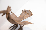 Angled view of the handmade bird casting's textured wings and geometric tail feathers.