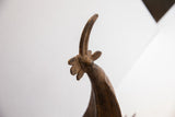 Angled view of the vintage African bird casting's textured, curved beak and crown.