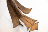 Stylized fan tail of a vintage African bird casting with incised wave and line details.