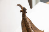 Upward view of the cast bird's head highlighting its curved beak and etched patterns.