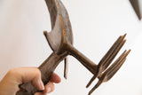 The rustic, hand-cast texture of the vintage African bird figure held for scale.
