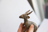 Side profile of the vintage antelope sculpture's head, showing its aged and textured surface.