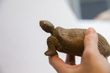 Side profile of the vintage tortoise sculpture showing its head and textured front leg.