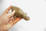 Vintage alligator sculpture with criss-cross pattern and aged patina held for scale.