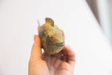 Vintage African fish casting held in hand, showing textured head with aged patina.
