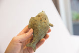 Vintage African fish casting held in hand, showing its scale and incised spiral patterns.
