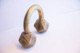 Angled profile of an antique African cuff bracelet with faceted, geometric ends.