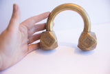 A hand holds the substantial antique African geometric cuff bracelet for scale.