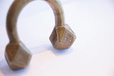 Etched geometric patterns and aged patina on the faceted terminal of an antique African bracelet.
