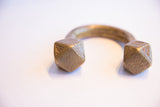 Geometric engravings and aged patina on the cube-shaped ends of an antique African cuff.
