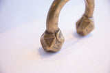 Hand-engraved geometric details on the faceted brass terminal of an antique African cuff.