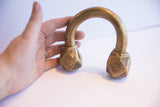 The scale and handcrafted form of an antique African cuff bracelet held in hand.