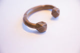 Finely crafted geometric stamp work on the cube-like end of an antique copper cuff.