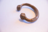 Stamped geometric details and warm patina on the terminal of an antique African cuff.