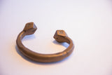 An antique African copper bracelet displaying its open cuff design and faceted ends.