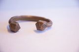 Faceted geometric terminals of an antique copper cuff showing a stamped detail.