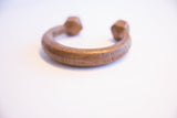 Engraved geometric patterns and aged patina on an antique African copper cuff bracelet.