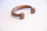 Angled view of the antique copper cuff's faceted terminal with etched geometric patterns.