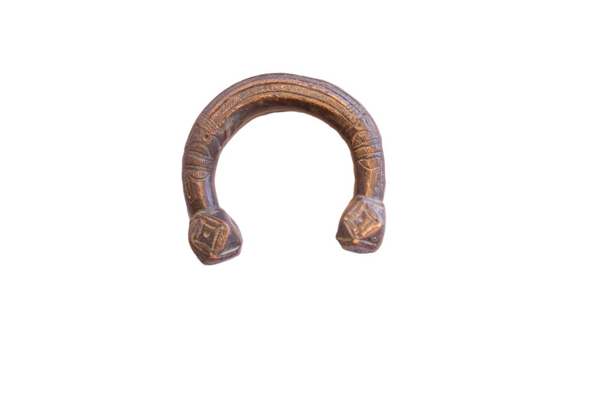 Antique African copper alloy cuff bracelet with an aged patina and etched geometric designs.
