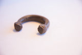 Faceted geometric terminals on an open antique African copper alloy cuff bracelet.