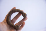Antique African cuff bracelet held to show its scale, curved form, and aged patina.