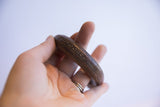 Antique African copper alloy cuff bracelet held in hand to show scale and texture.