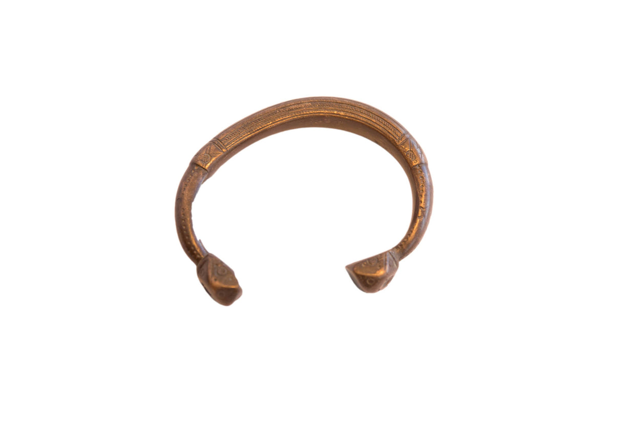 Antique African snake cuff bracelet with a warm metal patina and detailed etched patterns.