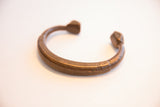The curved form and hand-etched details of an antique African cuff bracelet.