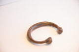 Curved form of the antique African snake cuff showing its aged, matte finish.