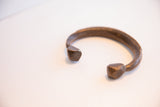 Carved snake head ends and aged patina on the antique African cuff bracelet.