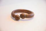 Aged patina on the rounded snake-head ends of an antique African cuff.